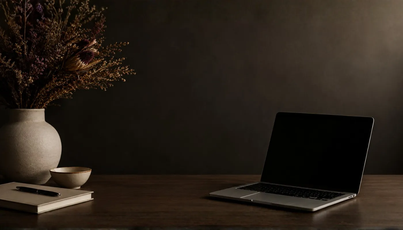 A wooden desk with a laptop, notebook, and coffee cup.